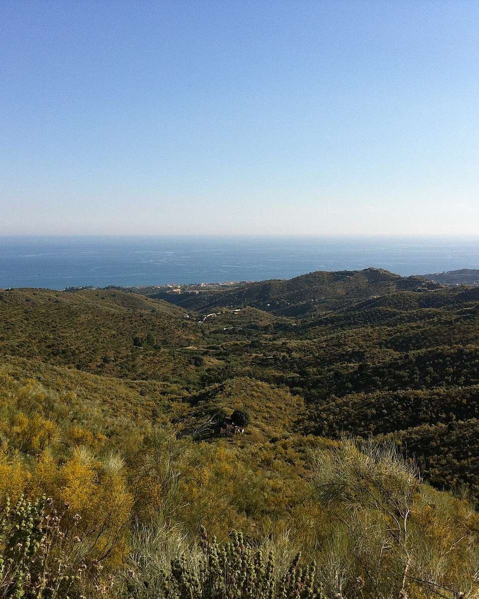 Montes de la Axarquía cubiertos de matorral, con el mar al fondo