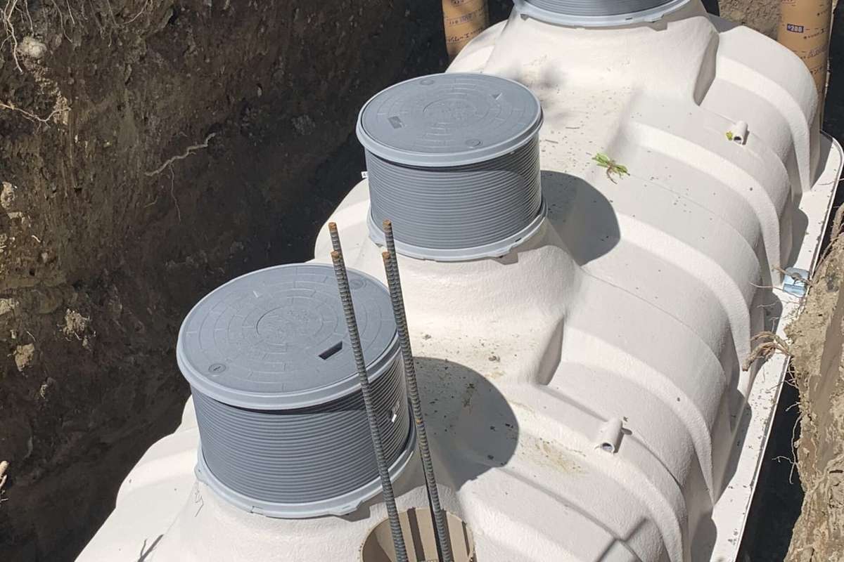 Fosa séptica prefabricada de plástico blanco con dos registros grises, dentro de una zanja